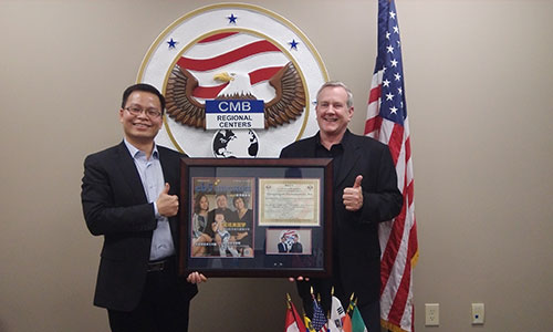 美成達(dá)小邱總（邱少波先生）接受CMB總裁Patrick F.Hogan先生贈送帶有陳先生一家采訪照片的雜志以及頒發(fā)給美成達(dá)的榮譽(yù)證書